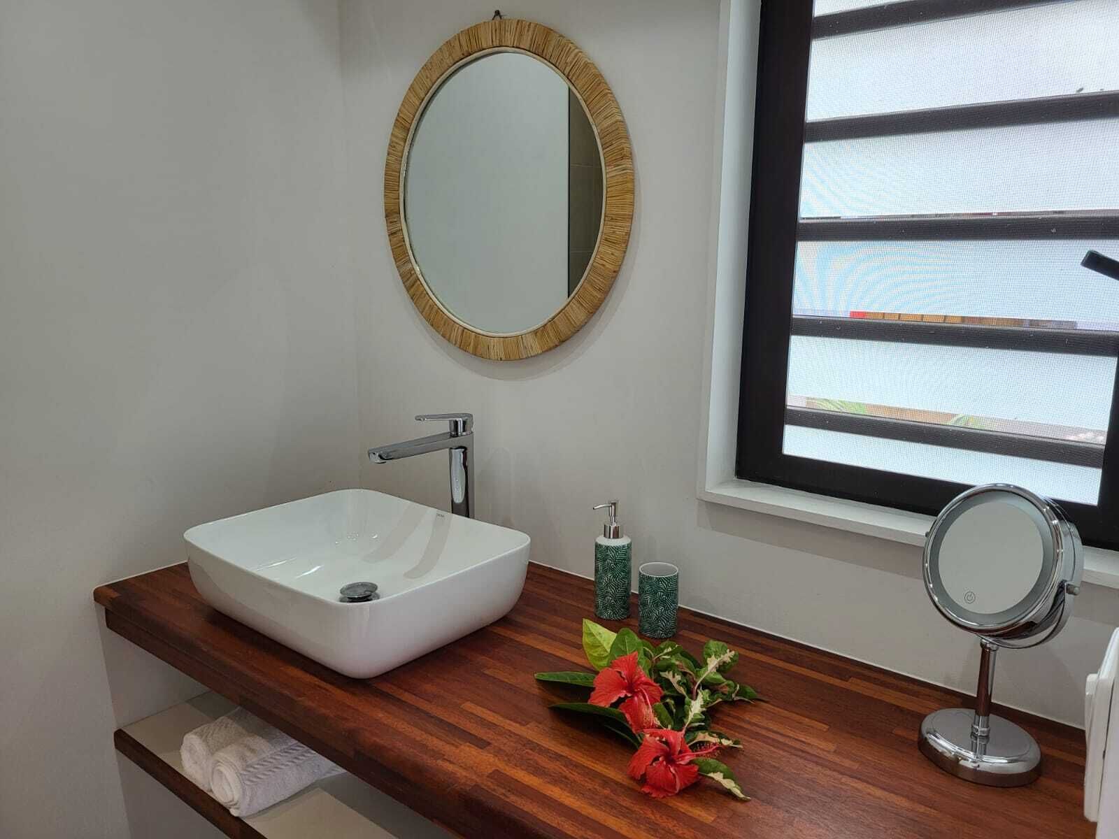 A bathroom with a white sink, a mirror, and a window with blinds.