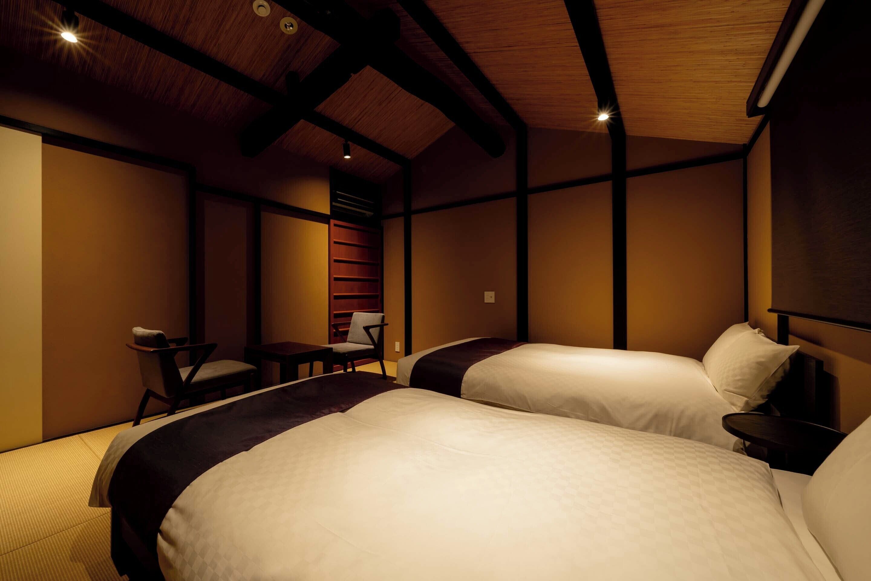 A hotel room with two beds, a desk, and a chair.