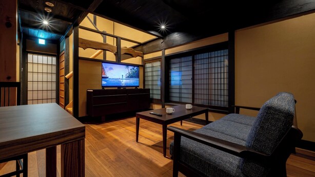 Ett traditionellt vardagsrum i japansk stil med tatamimattor på golvet, ett lågt träbord, en soffa och en tv.