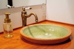 Un lavamanos con grifo de bronce y lavabo de cerámica verde.