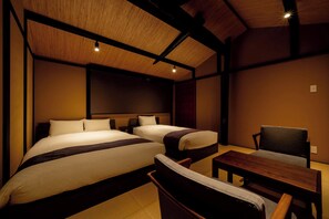 Habitación de hotel con dos camas, una mesa de madera y una silla.