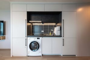 A compact kitchen with a built-in washer, a microwave, and a stove. - More Than Sokcho Lighthouse Branch (Sokcho)