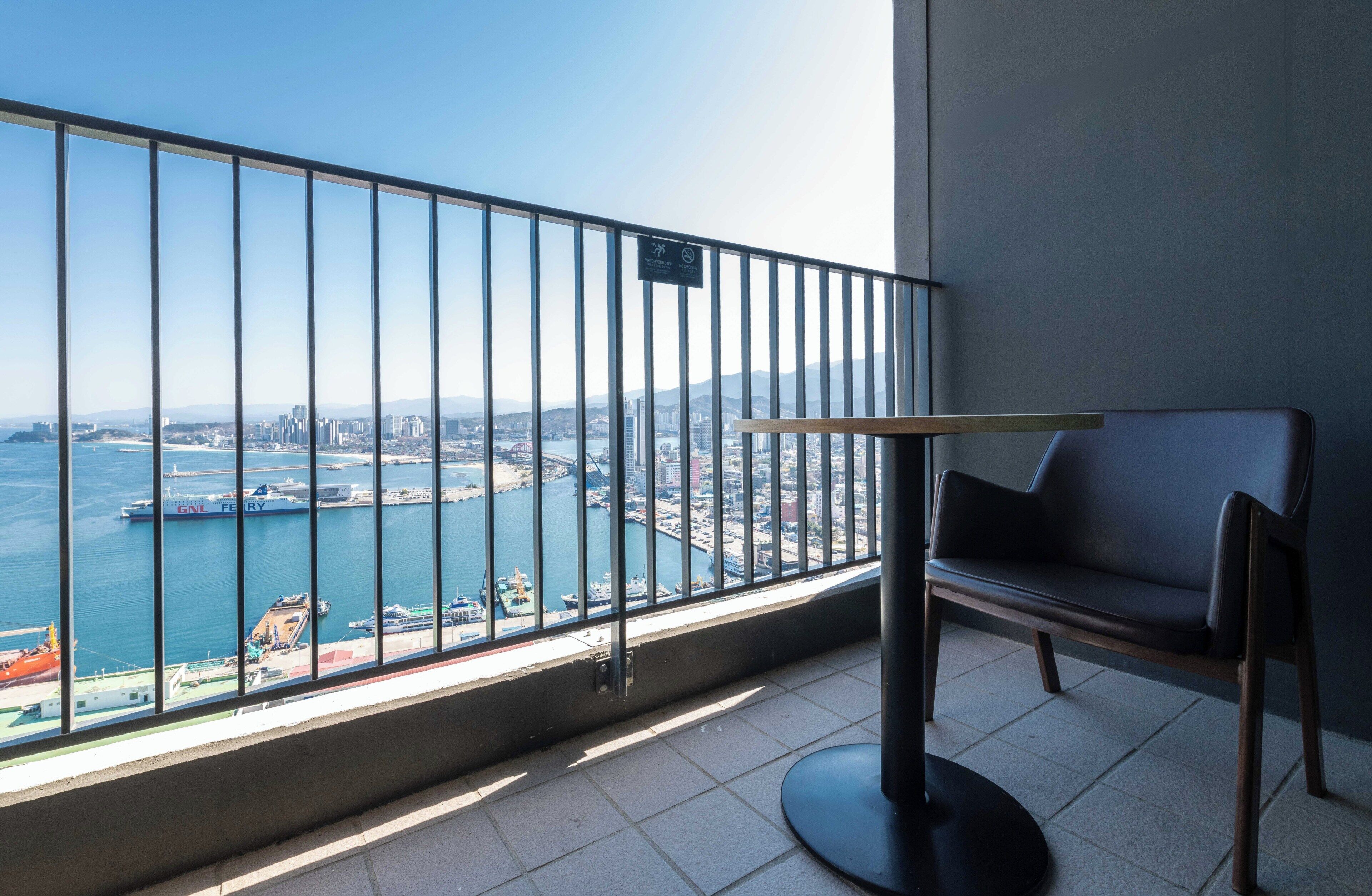 A balcony with a metal railing, a chair, and a small table.