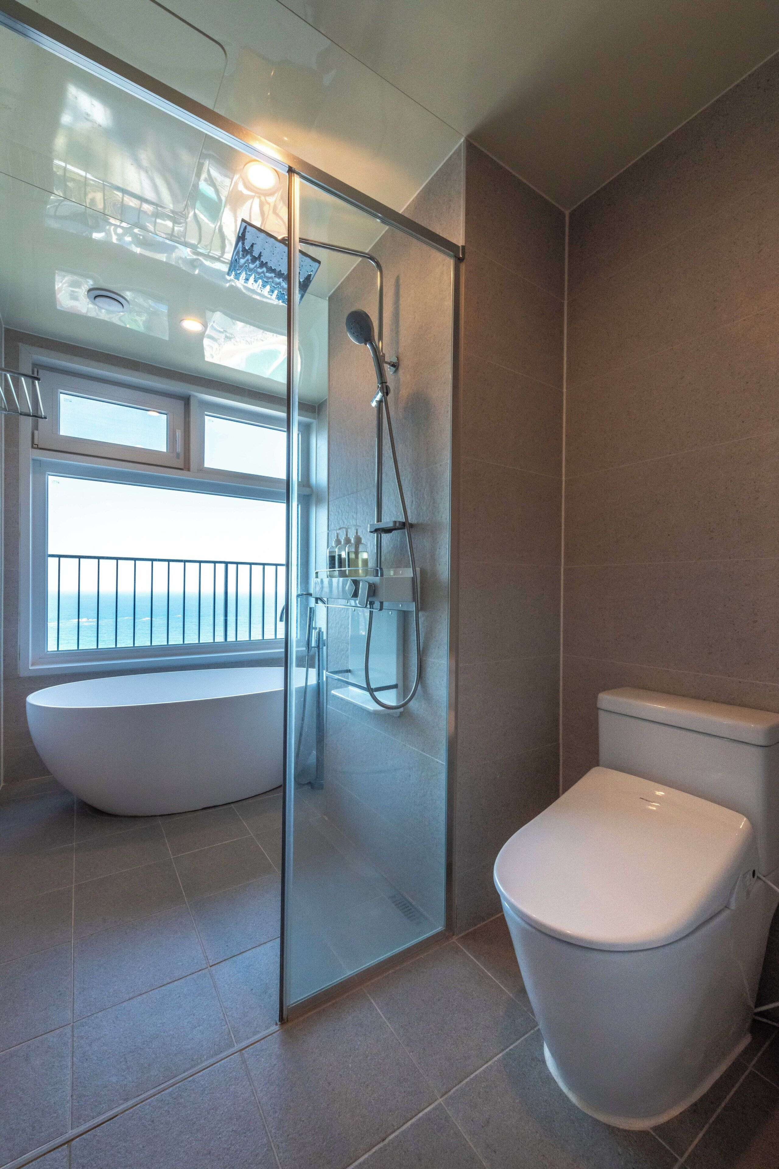 Een badkamer met een douche met glazen wand, een badkuip en een toilet.