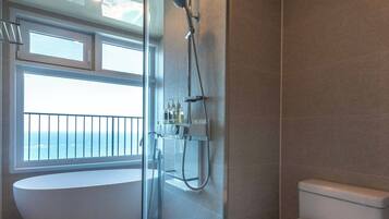 Een badkamer met een douche met glazen wand, een badkuip en een toilet.