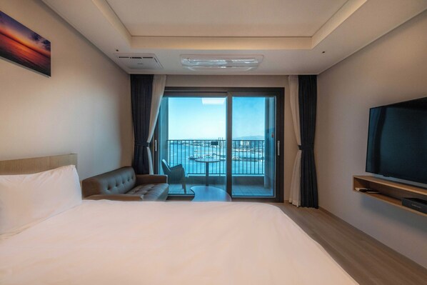A hotel room with a bed, a sofa, a TV, a balcony with a view of the sea, and a painting on the wall. - More Than Sokcho Lighthouse Branch (Sokcho)