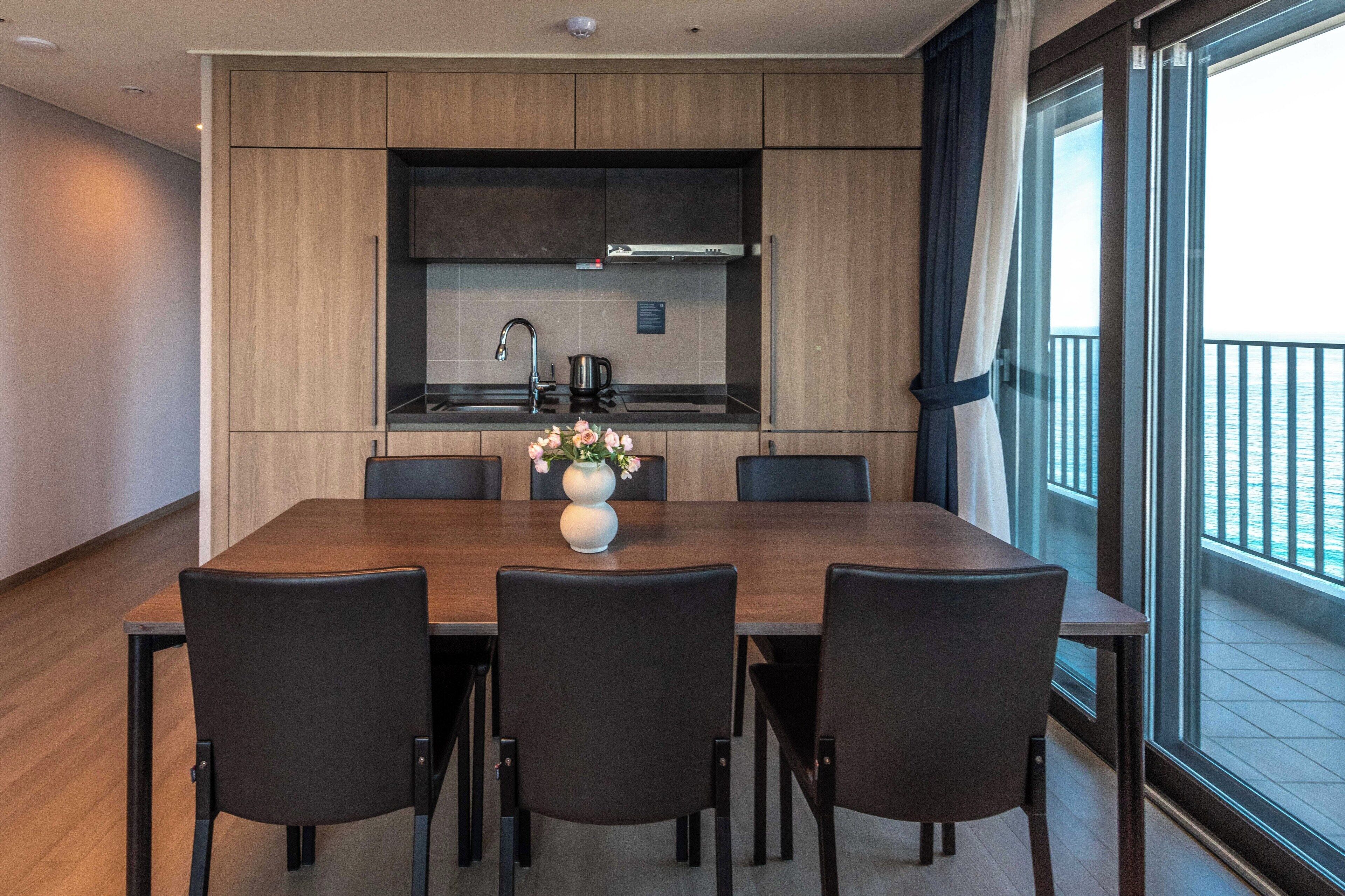 Una cocina moderna con comedor, ventanas amplias y vista al mar.