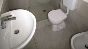 Un bany amb dutxa de vidre, un lavabo i un vàter.