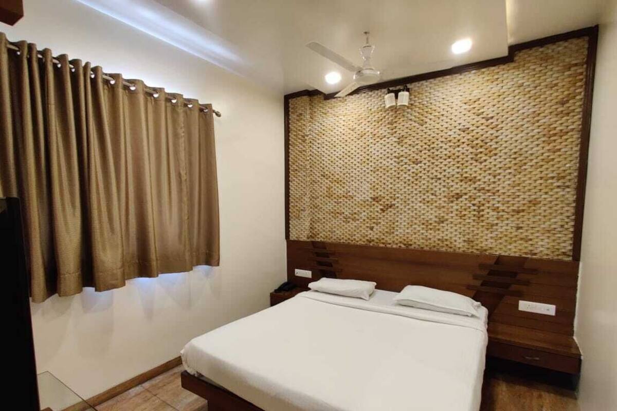 A neatly arranged bedroom with a bed, curtains, a wall-mounted headboard, and a ceiling fan.