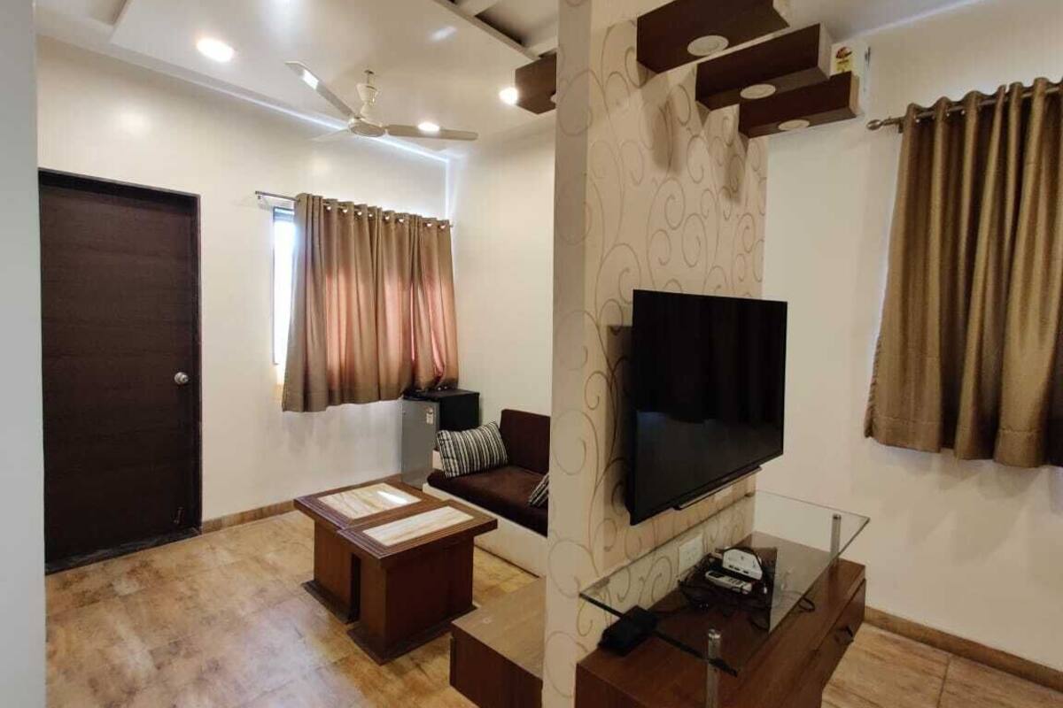 A living room with a flat-screen TV, a sofa, a coffee table, and a ceiling fan.