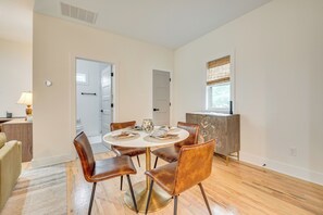 Un coin repas comprenant une table ronde, six chaises et un buffet en bois.
