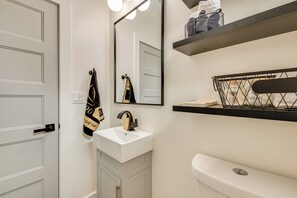 Une salle de bain avec un lavabo blanc, un miroir, un porte-serviettes et des toilettes.