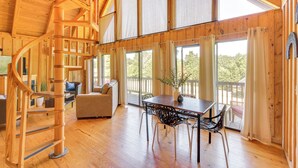 A wooden interior with a spiral staircase, a dining area with a table and chairs, and large windows offering views of the outdoors. - Lake Keowee Retreat: Idyllic Six Mile Cabin! (Six Mile)