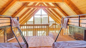 An attic bedroom with wooden beams, bunk beds, and a large window. - Lake Keowee Retreat: Idyllic Six Mile Cabin! (Six Mile)