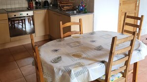 A kitchen with a dining table, chairs, a stove, and a sink. - Charming 2-bedroom house in soothing Cuillé with WiFi (Cuillé)