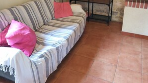 A cozy living room with a striped sofa, a small black side table, and a stone wall. - Charming 2-bedroom house in soothing Cuillé with WiFi (Cuillé)