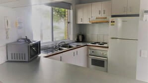 A kitchen with a microwave, stove, sink, and cabinets. - U09 Tripcony 2 Bedroom w Balcony (Caloundra)