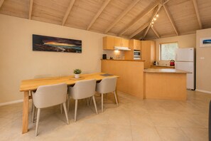Une cuisine avec une table en bois, des chaises, des placards et un réfrigérateur.