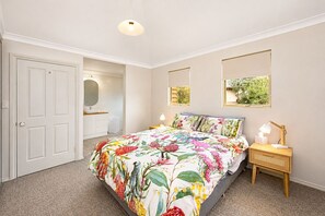 Une chambre à coucher avec une couvre-lit à motifs floraux, une lampe de chevet et un miroir au mur.