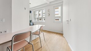A modern kitchen with white cabinetry, a wooden countertop, and two metal chairs. - Art and comfort near the Bastille (Paris)