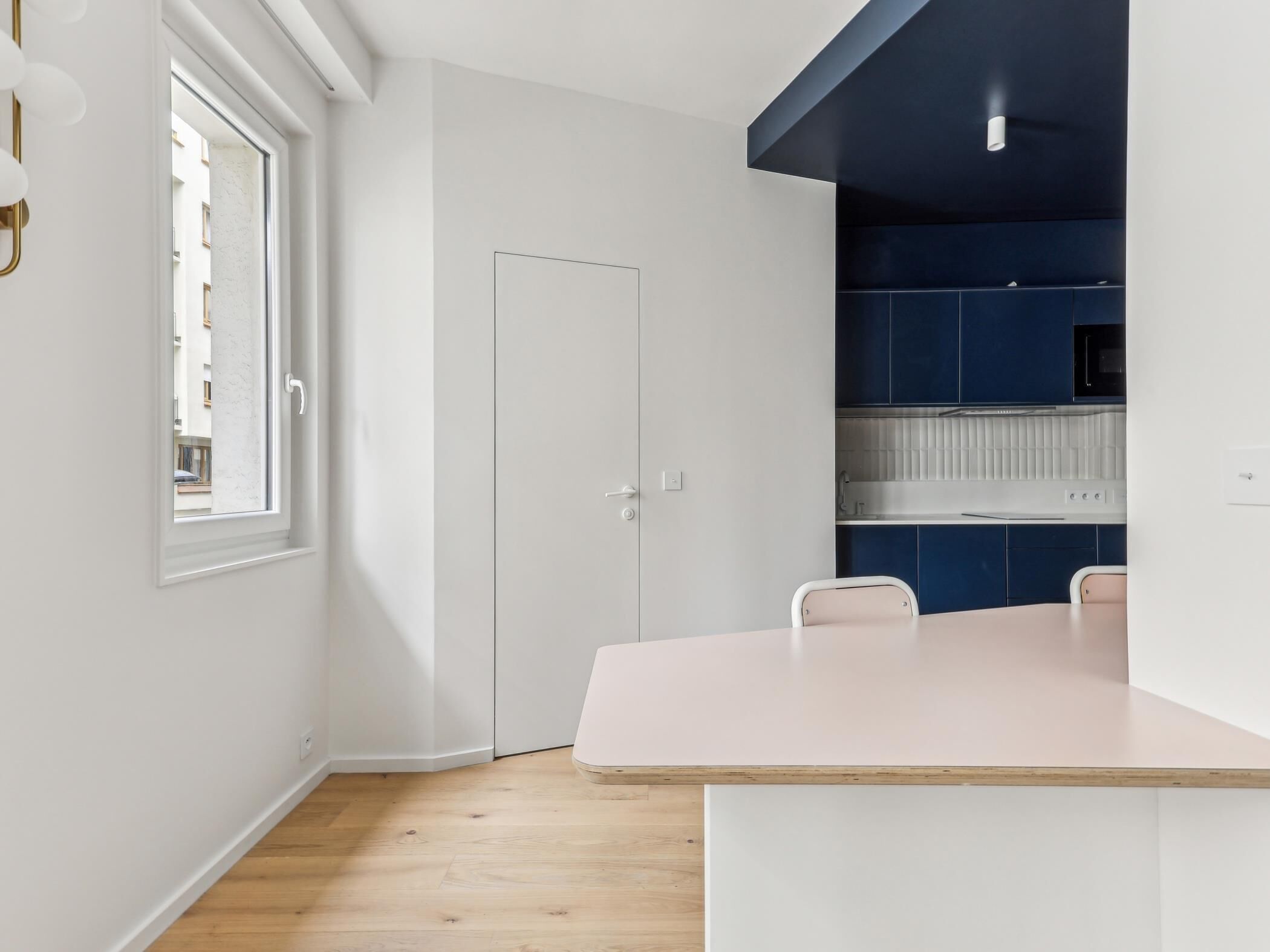 A modern kitchen with white cabinets, a wooden countertop, and a window with a view of the outside.