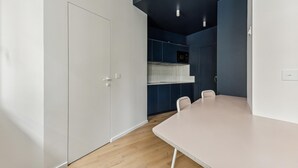 A modern kitchen with white cabinets, a black microwave, and a white countertop. - Art and comfort near the Bastille (Paris)