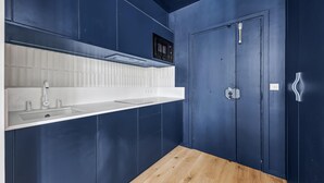 A compact kitchen with a wooden countertop, white backsplash, and dark blue walls. - Art and comfort near the Bastille (Paris)