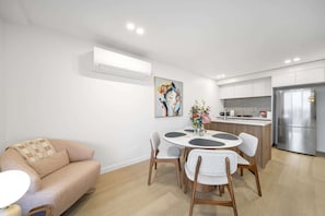 Eine moderne Küche mit eingebautem Kühlschrank, einem Esstisch mit Stühlen und einer Couch.