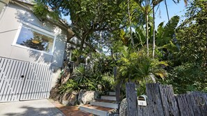 A residential property with a gated entrance, a wooden fence, and a staircase leading to a house. - 2-Bed Beach House in Burleigh Heads Amidst Nature (Burleigh Heads)