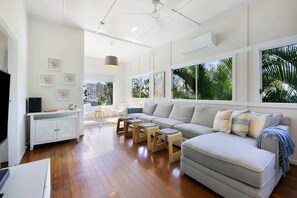 A modern living room with a sectional sofa, wooden coffee table, and a dining area with a white cabinet and chairs.