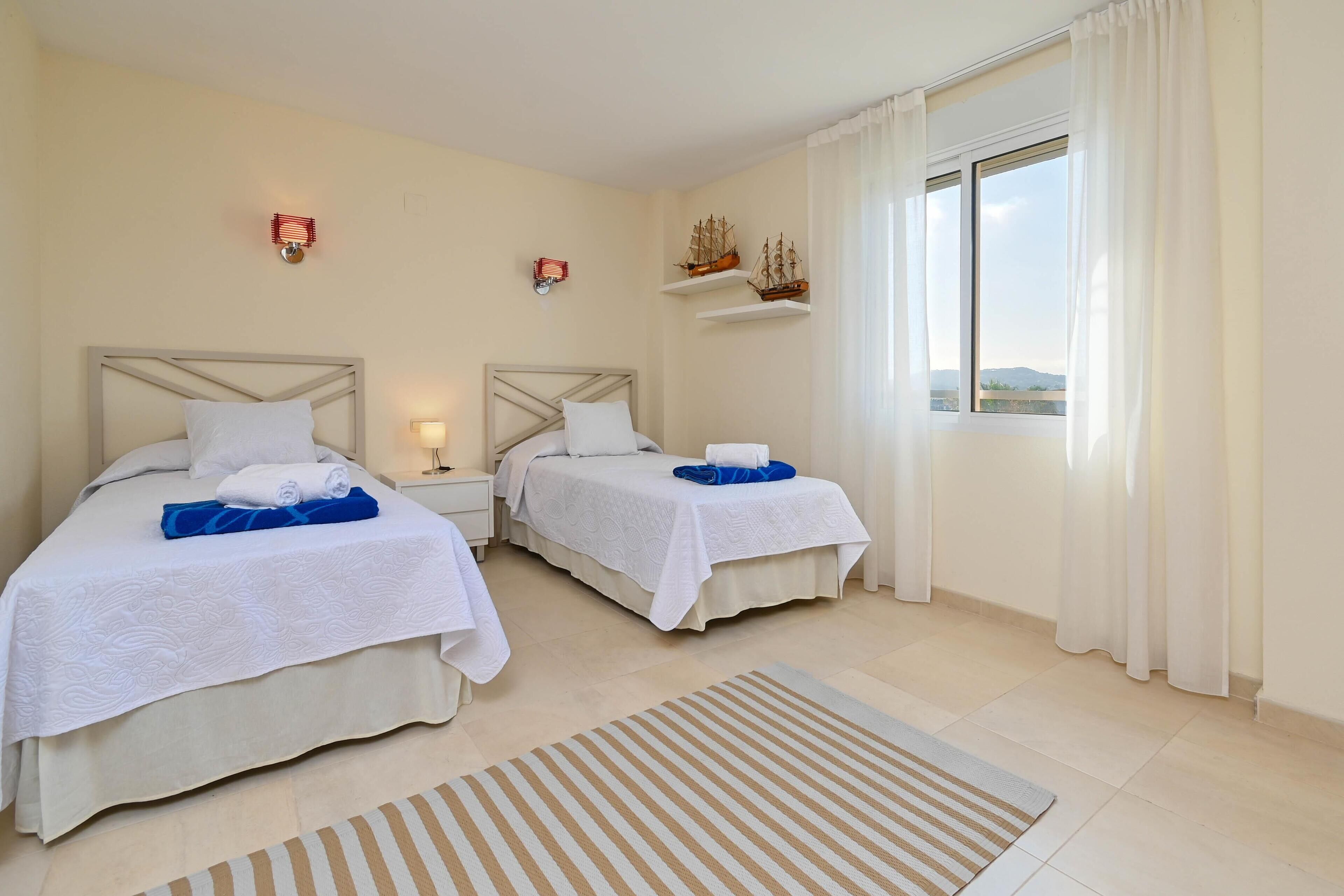 Een hotelkamer met twee bedden, een groot raam met gordijnen en uitzicht op het landschap.