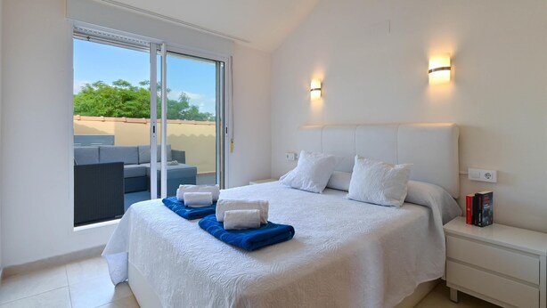 Une chambre à coucher avec un lit, une table de chevet et une vue sur l’extérieur.