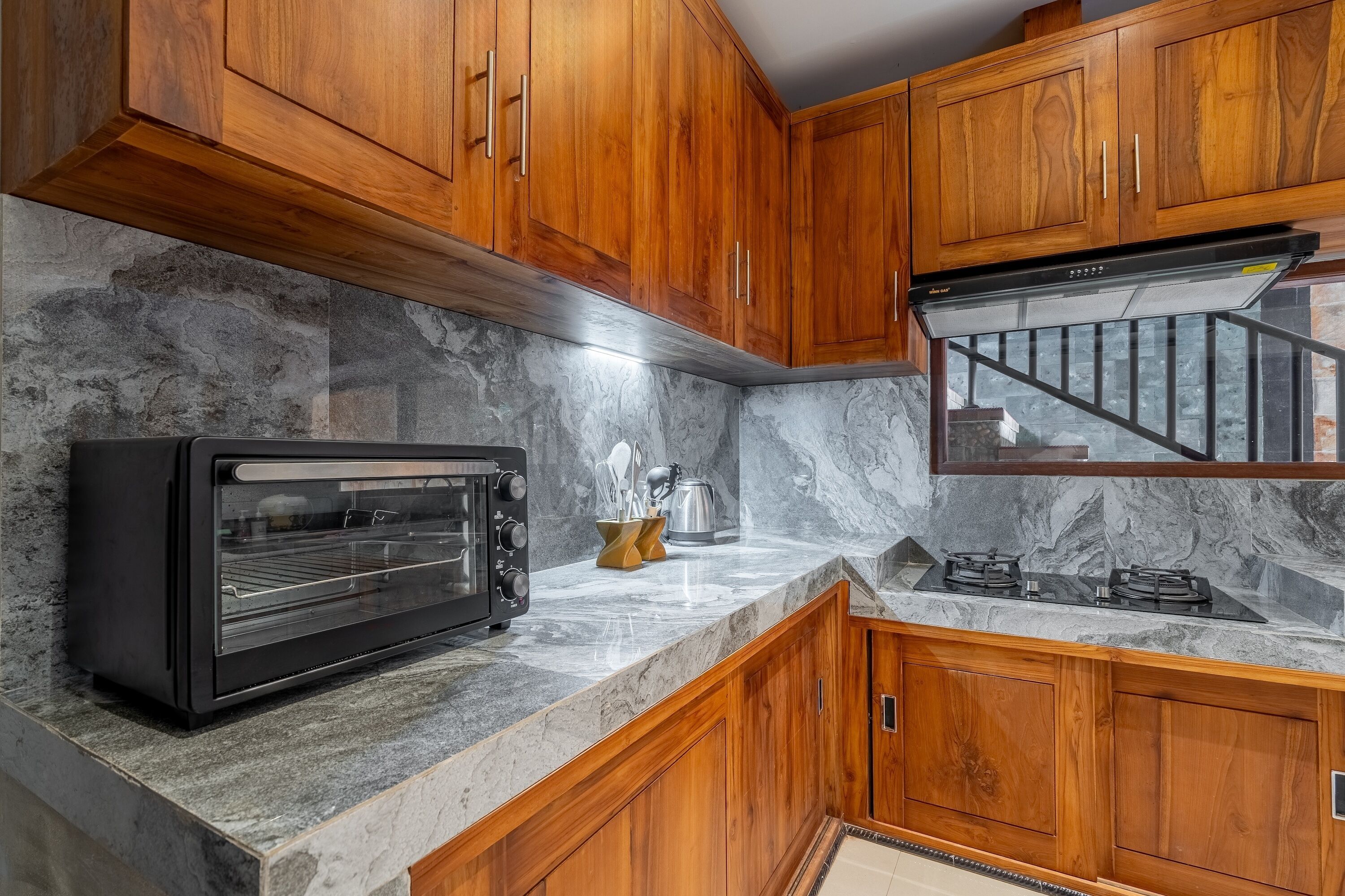 A kitchen with wooden cabinets, a built-in oven, a gas stove, and a marble backsplash.