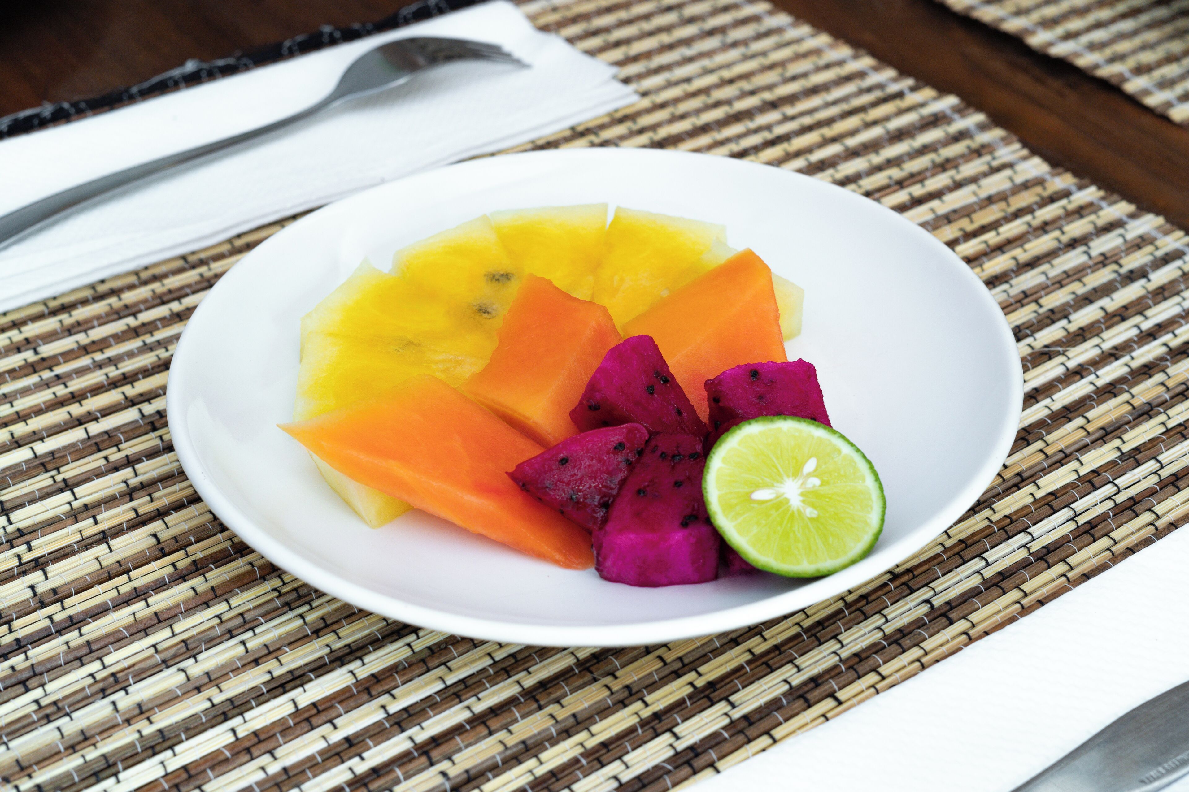 A plate of fruit on a woven mat.