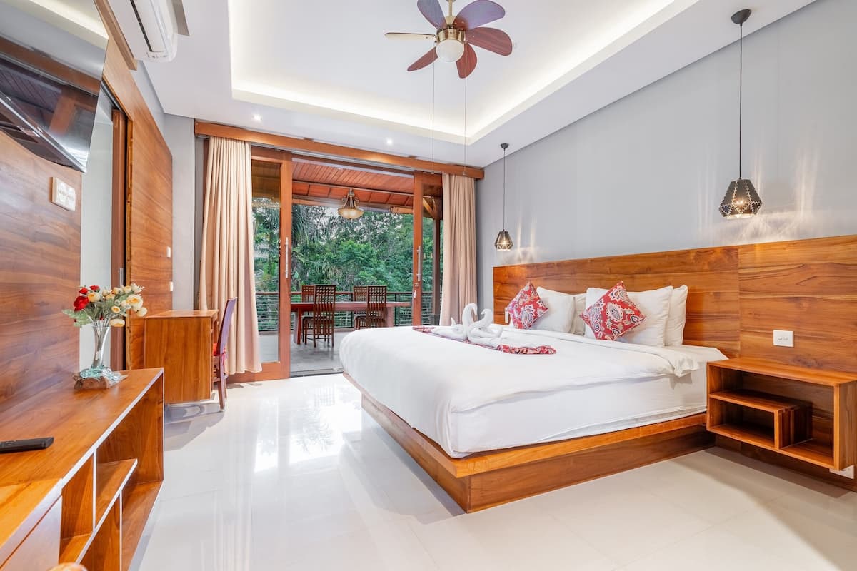 Une chambre moderne avec un grand lit, une tête de lit en bois et un ventilateur de plafond.