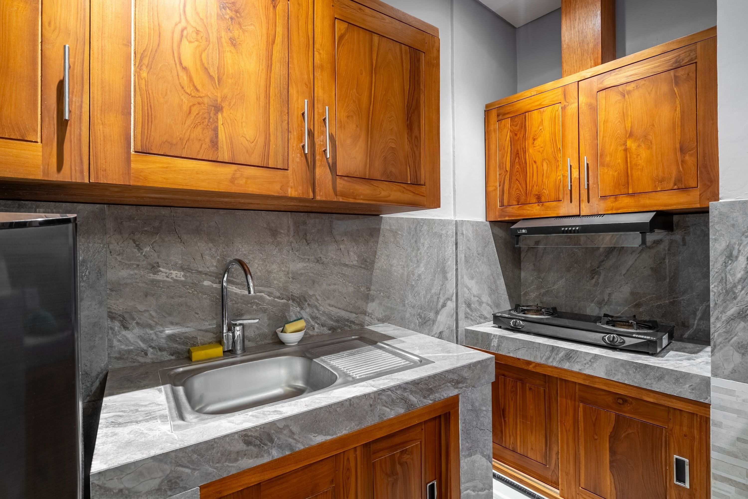 Una cocina moderna con armarios de madera, un lavamanos de acero inoxidable y una estufa a gas.