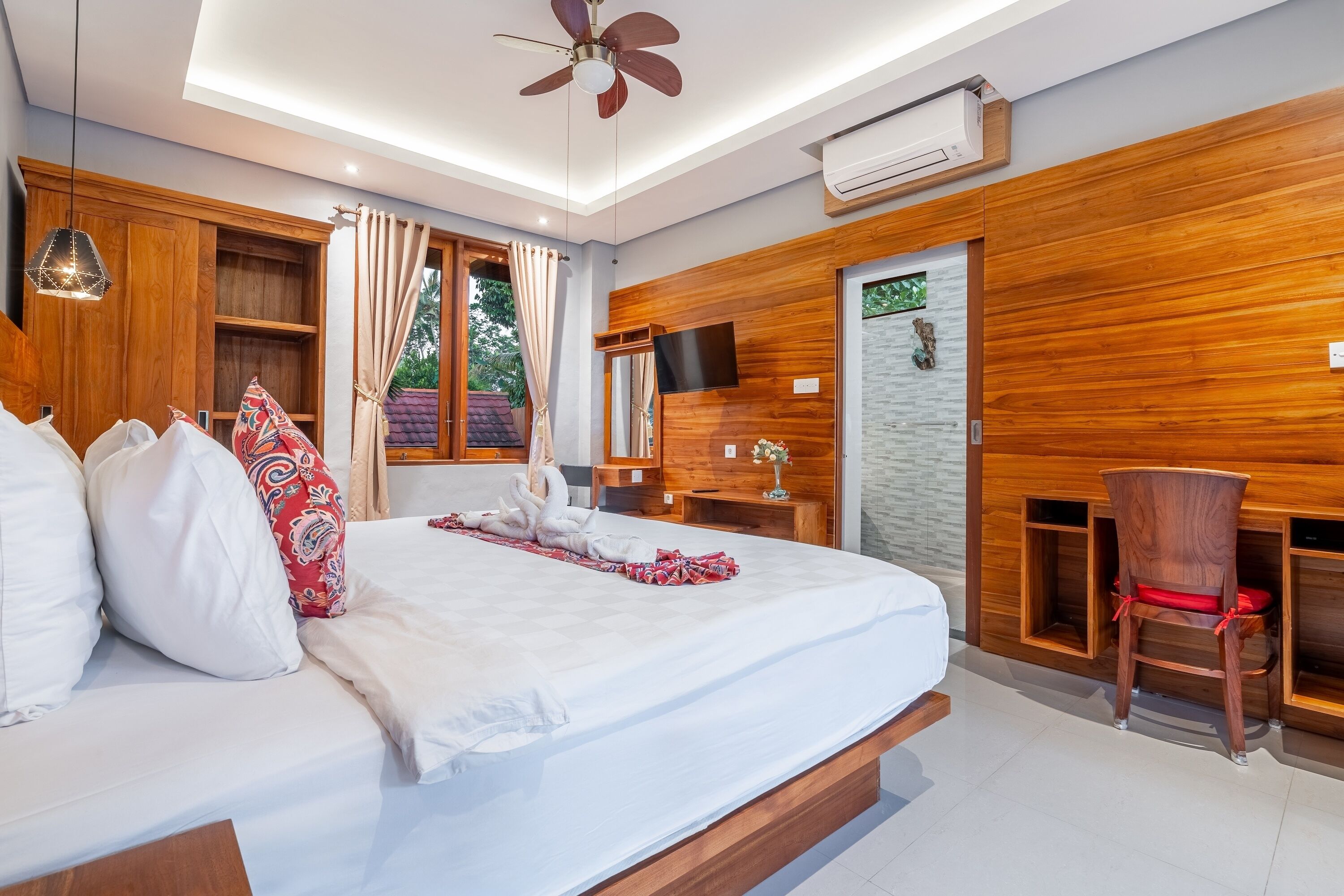 A modern hotel room with a large bed, wooden paneling, a desk, and a chair.