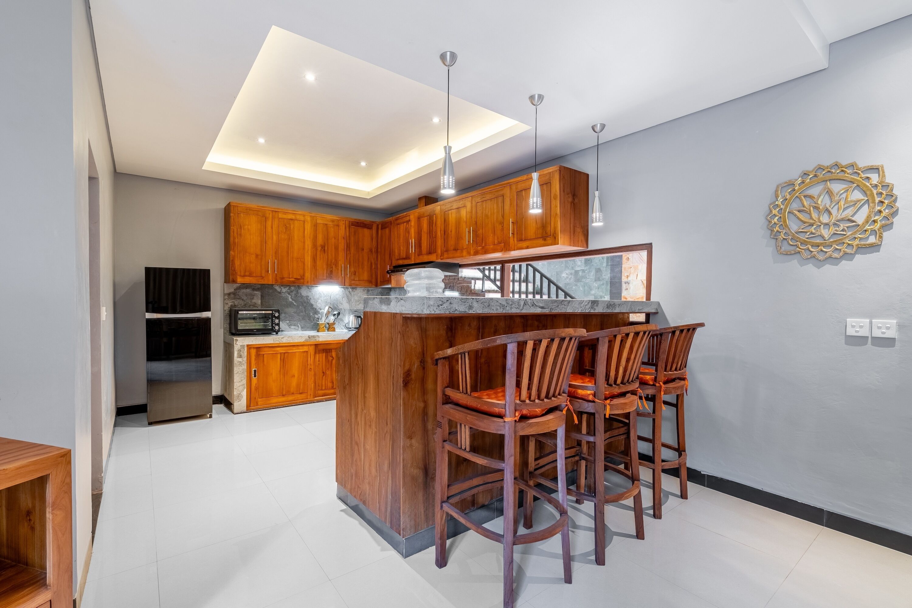 Una cocina moderna con armarios de madera, encimera de mármol y una isla central con taburetes de bar.