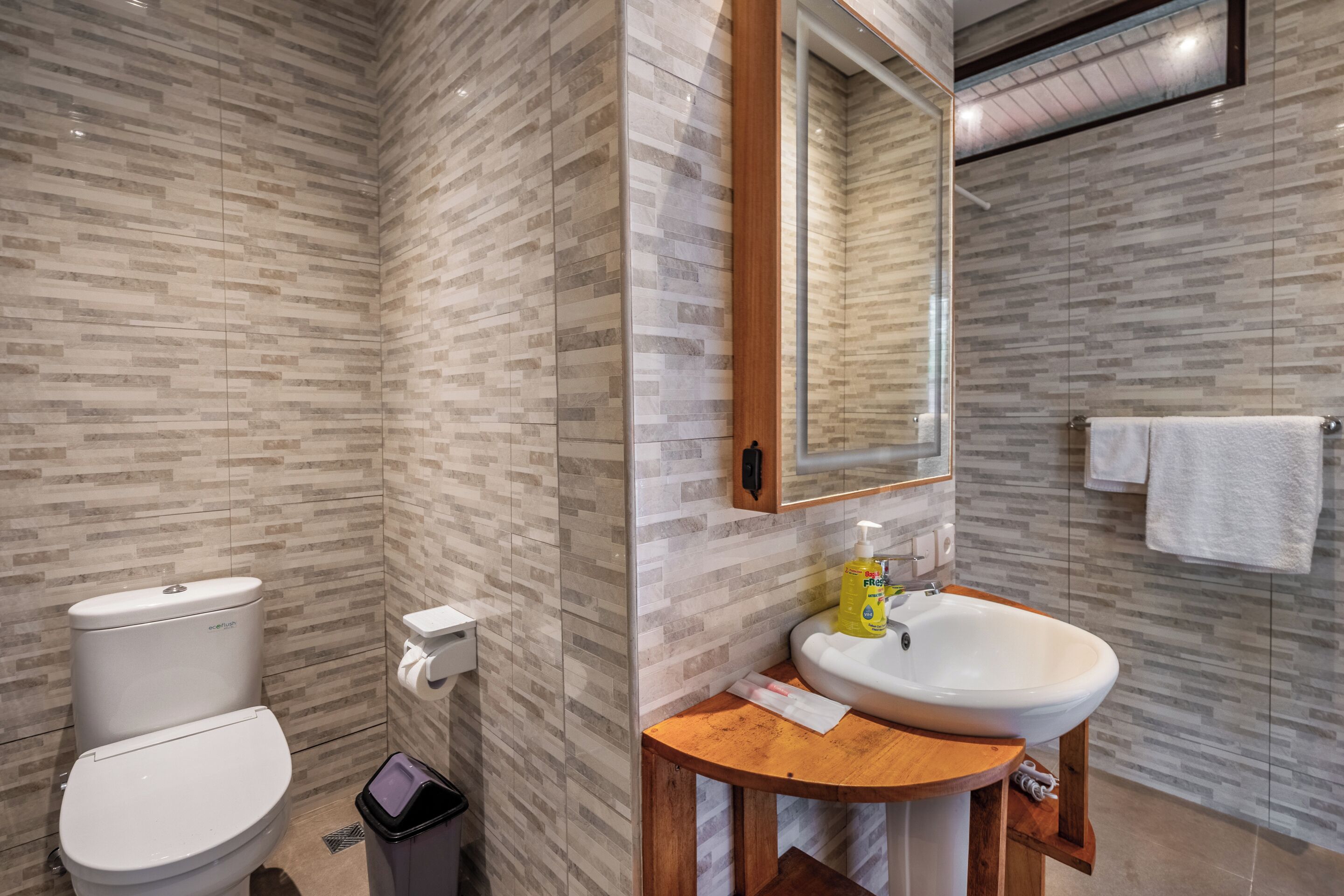 A modern bathroom with a toilet, sink, and mirror.