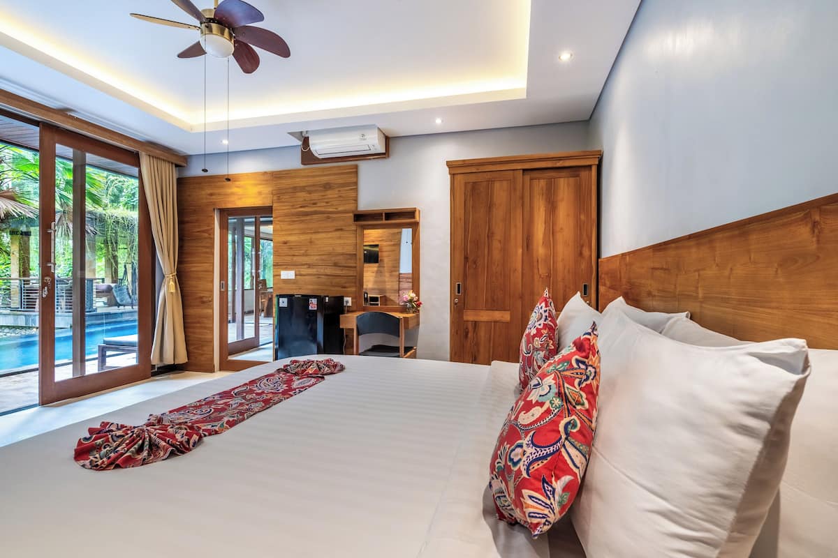 Une chambre avec un grand lit, un bureau et une vue sur une piscine.