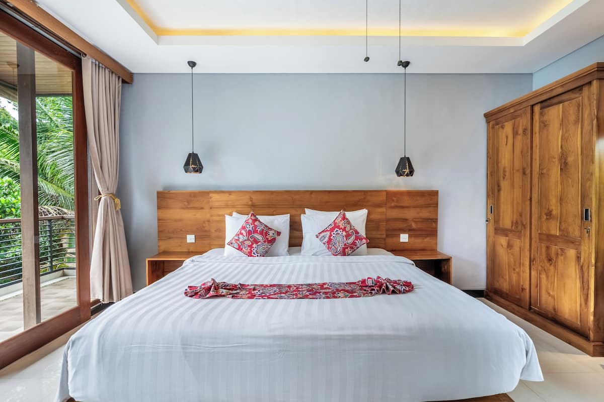 Une chambre à coucher avec un grand lit, une tête de lit en bois, deux tables de chevet et une armoire.