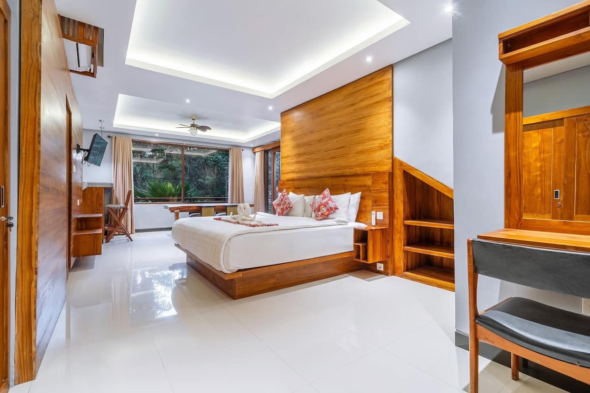 Une chambre moderne avec un grand lit, une tête de lit en bois et un bureau intégré.