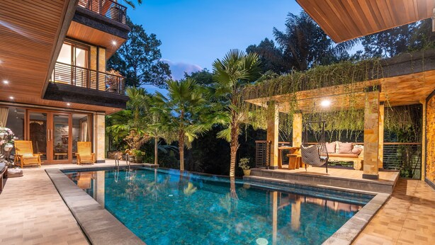 A modern house with a swimming pool, wooden deck, and outdoor seating area. - Maru Fortuna Villa by Aayan (Gianyar)