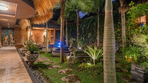 A well-lit outdoor area with a stone pathway, tropical plants, and a water feature. - Maru Fortuna Villa by Aayan (Gianyar)