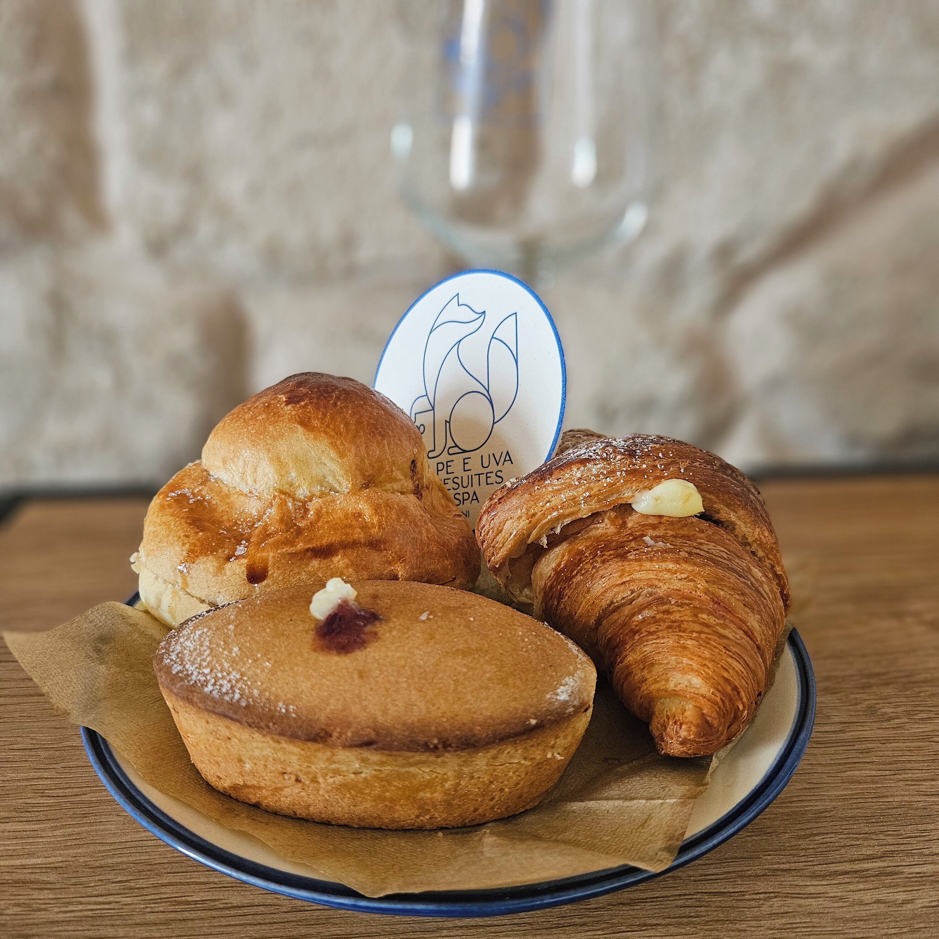 A plate with three pastries, a coffee cup, and a logo on a napkin.