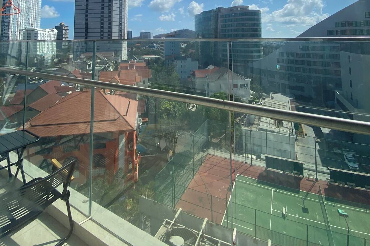 Un immeuble de grande hauteur offrant une vue sur le paysage urbain, avec différents bâtiments et un terrain de sport.