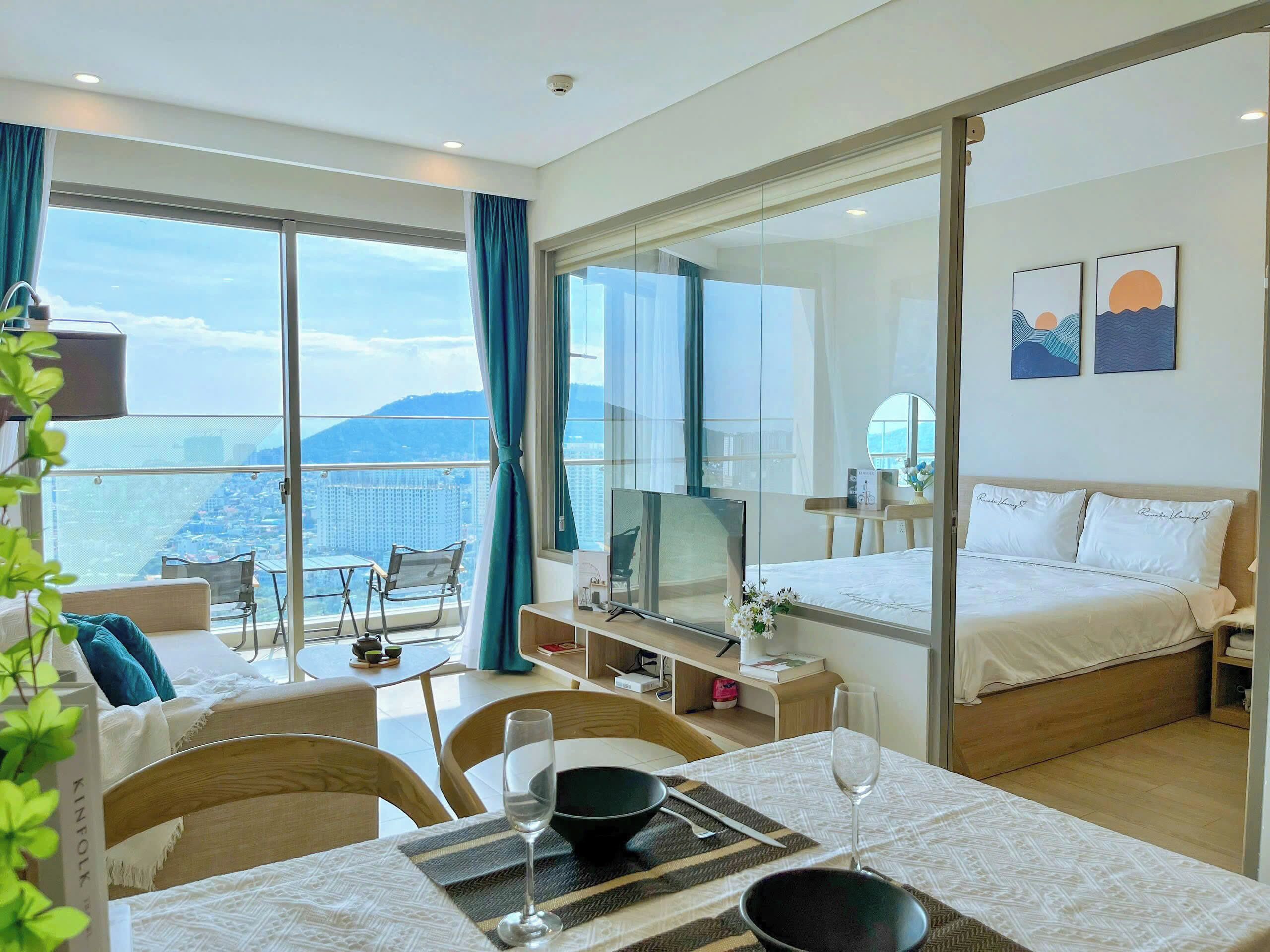 Una habitación de hotel con balcón, cama, zona de comedor y televisión.