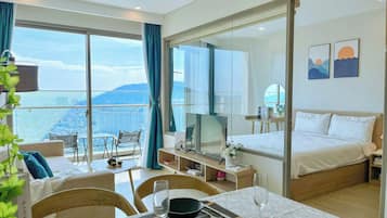 Una habitación de hotel con balcón, cama, zona de comedor y televisión.