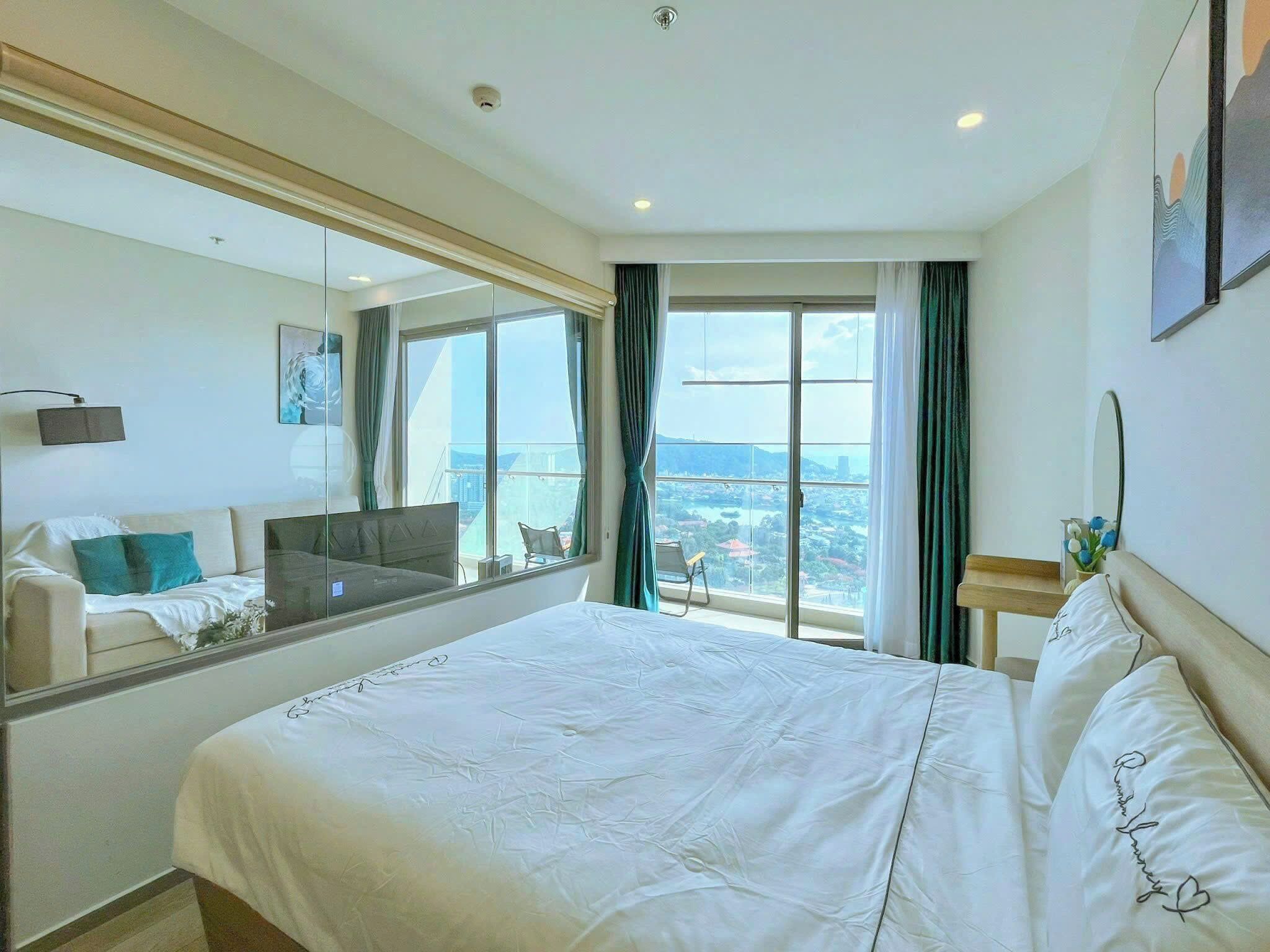 Habitación de hotel con una cama grande, un sofá, televisión y vistas a la ciudad.