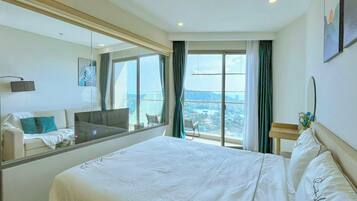 Habitación de hotel con una cama grande, un sofá, televisión y vistas a la ciudad.